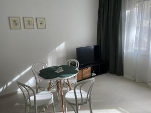Cette chambre dispose d'une table, de chaises et d'une télévision. dans l'établissement SKAU Dunajska Family Two Bedroom Apartment Old Town, à Bratislava