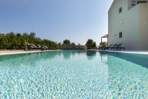 a swimming pool with chairs and a building at Alekos Beach Houses-Akrotiri Suites in Kounopetra