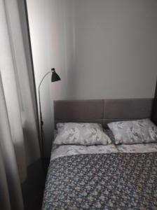 a bed with two pillows and a lamp in a room at Rose Apartament in Brwinów