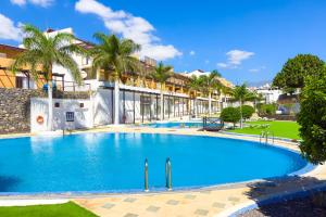 een zwembad in een resort met palmbomen bij 4x Bedrooms Poolside Apartment in Amarilla Golf in San Miguel de Abona