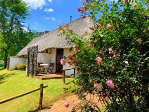 a thatch roofed cottage with a table and flowers at Bramleigh Farm in Nottingham Road