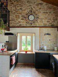 een keuken met een raam en een klok aan de muur bij La Jousselinie in Saint-Auvent