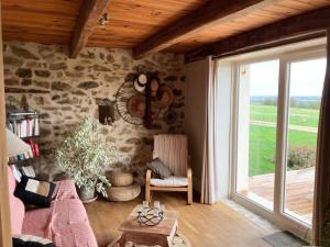 sala de estar con pared de piedra y ventana en La Jousselinie en Saint-Auvent