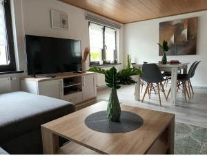 ein Wohnzimmer mit einem TV und einer Vase auf dem Tisch in der Unterkunft Zum Rosenhügel in Hellenthal