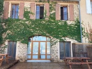 a building covered in ivy with benches and windows at Maison indépendante, canal du Midi, Piscine in Homps