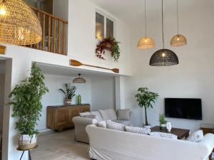 una sala de estar con muebles blancos y macetas. en Maison indépendante, canal du Midi, Piscine, en Homps
