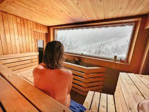 una persona sentada en una sauna mirando por la ventana en Basecamp Andermatt, en Andermatt