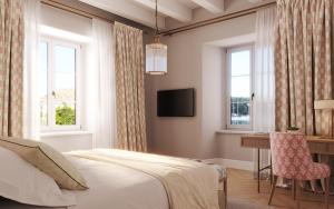 a bedroom with a bed and a desk and windows at Hotel Supetar in Cavtat