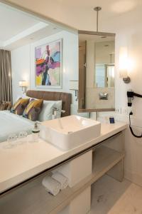 a white bathroom with a sink and a bed at The Ashtan Sarovar Portico in New Delhi