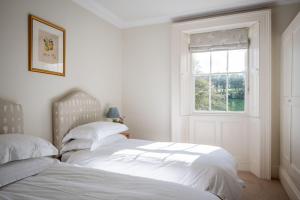 two beds in a white bedroom with a window at Little Oak in Holbeton