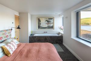 a bedroom with a bath tub and a bed and a window at Horsepool Boathouse in Salcombe