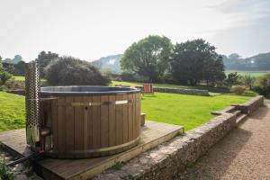 a hot tub sitting on a wooden deck in a field at Hummingbird House in Holbeton