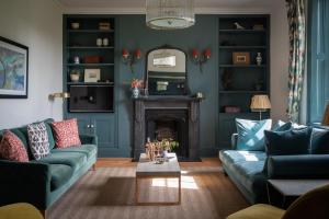 a living room with blue couches and a fireplace at Hummingbird House in Holbeton