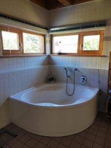 a large white tub in a bathroom with two windows at Ferienhaus Haslberger in Waging am See