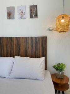 um quarto com uma cama com uma cabeceira em madeira e uma mesa em Emerald Guest House type kansas Purwokerto em Banyumas
