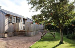 una mesa de picnic junto a una valla con un árbol en Holiday Lodges with hot tub & Cosy Cabins - Greenway Farm, Drybrook, Forest of Dean, en Drybrook