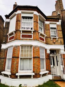 uma casa de tijolos vermelhos com janelas brancas e uma porta em Victorian Woods BnB em Londres