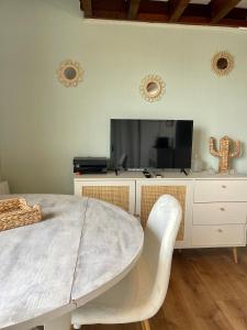 uma sala de estar com uma televisão e uma mesa branca em La Cabane Rennaise em Rennes