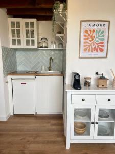 uma cozinha com armários brancos e um lavatório em La Cabane Rennaise em Rennes