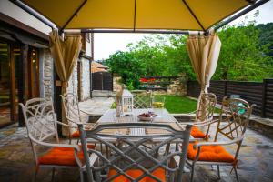 Veliko Tarnovo Villa Lora في فيليكو ترنوفو: طاولة وكراسي مع مظلة على الفناء