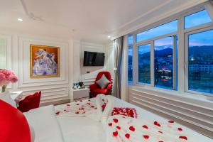 a bedroom with a bed and a red chair and window at Diamond Hotel Sapa in Sa Pa