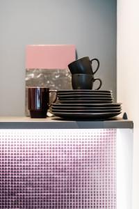 ein Regal mit Teller und Tassen und einer rosa Schachtel in der Unterkunft Exklusive Design Appartement BlackBerry Neubau in Pfungstadt