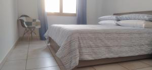 - une chambre avec un lit, une couverture et une chaise dans l'établissement FeA, à Capoterra