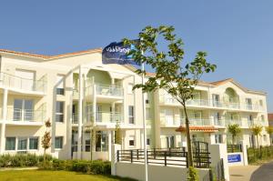 a large white apartment building with a blue water bottle at Résidence Goélia La Grande Plage in Saint-Gilles-Croix-de-Vie
