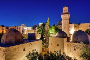 una vista de la ciudad por la noche con una mezquita en Cityland Hotel Baku, en Baku