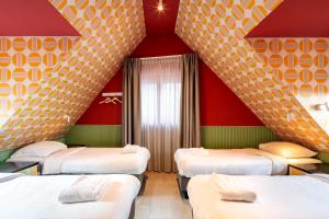 four beds in a room with red and yellow walls at Budget Hotel Tourist Inn in Amsterdam