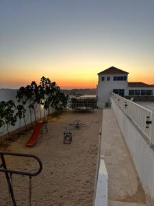 a sandy beach with a playground and a building at منتجعات روابي القمر 