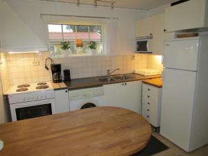 a kitchen with white appliances and a wooden table at DeLay's Guest House in Ängelholm