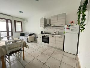 Il comprend une cuisine équipée d'un réfrigérateur blanc, d'une table et d'un canapé. dans l'établissement FeA, à Capoterra