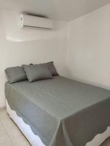 Bett in einem weißen Zimmer mit Avertisation in der Unterkunft Casa na Praia de itacimirim Vila Maria in Camassari