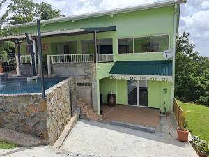 Cette maison verte dispose d'une terrasse couverte et d'un balcon. dans l'établissement Bas de Villa FloriRose, à Rivière-Salée