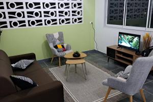 - un salon avec un canapé, des chaises et une télévision dans l'établissement Bas de Villa FloriRose, à Rivière-Salée