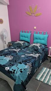 - une chambre dotée d'un lit avec un mur violet dans l'établissement Bas de Villa FloriRose, à Rivière-Salée