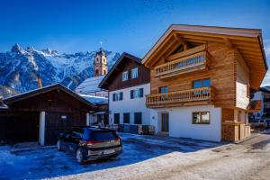 um carro estacionado em frente a uma casa com montanhas em Alpenloft 2 em Mittenwald