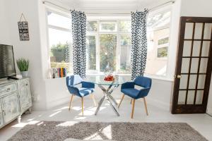 uma sala de jantar com uma mesa de vidro e 2 cadeiras azuis em Modern flat, sleeps 4, close to beach,Parking,WiFi - Queens Park Views em Bournemouth