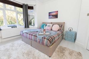 a bedroom with a bed with a blue nightstand and windows at Modern flat, sleeps 4, close to beach,Parking,WiFi - Queens Park Views in Bournemouth