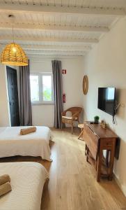 a bedroom with two beds and a tv and a table at Cantinho de Milfontes 1 Twin in Vila Nova de Milfontes
