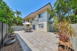 a patio with chairs and an umbrella in front of a house at Nightcliff Foreshore Getaway - McKay Gardens in Nightcliff