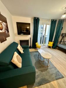 ein Wohnzimmer mit einem grünen Sofa und einem Tisch in der Unterkunft Appartement avec vue sur jardin Paris-Disney-Parking privé 'PKN MEAUX' in Meaux