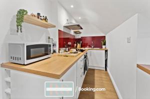 a kitchen with white and red walls and a microwave at Two Bedroom Apartment By Rutland Stays Short Lets & Serviced Accommodation With Parking in Oakham