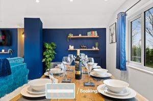 a dining room with blue walls and a table with wine glasses at Two Bedroom Apartment By Rutland Stays Short Lets & Serviced Accommodation With Parking in Oakham