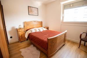 um quarto com uma cama de madeira e uma janela em Bel appartement entier, privé 5 Mn de Metz em Longeville-lès-Metz
