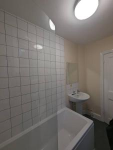 a white bathroom with a tub and a sink at Spacious & Budget Friendly 5 Bed Home! in Maidenhead
