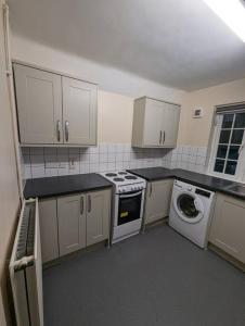a kitchen with a stove and a washing machine at Spacious & Budget Friendly 5 Bed Home! in Maidenhead
