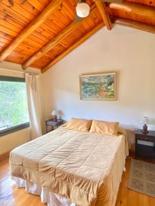 Un dormitorio con una cama grande en una habitación con techos de madera. en Cabañas Villa Luz en Salsipuedes