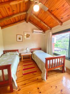 1 dormitorio con 2 camas y techo de madera en Cabañas Villa Luz en Salsipuedes